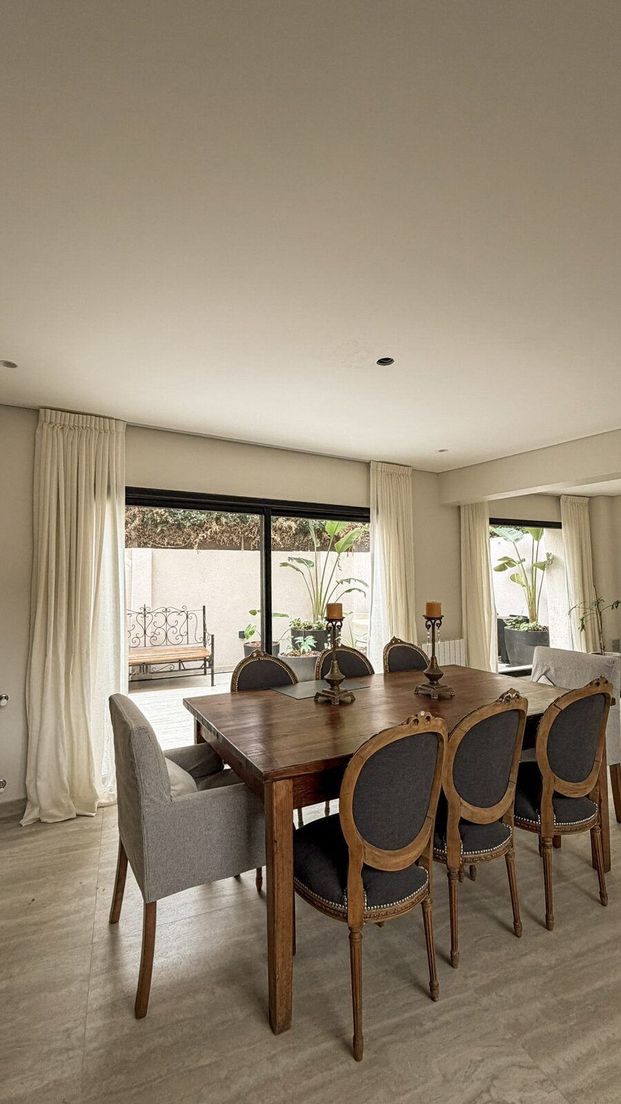 Comedor con cortinas claras junto a ventanales.