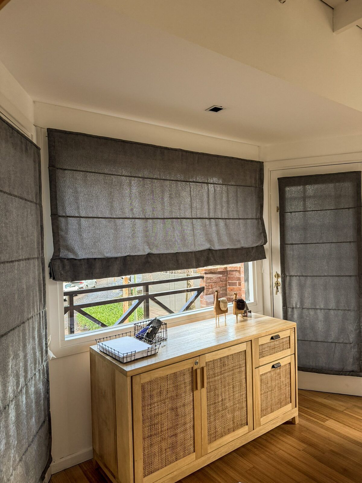 Cortinas romanas grises en una ventana y una puerta.