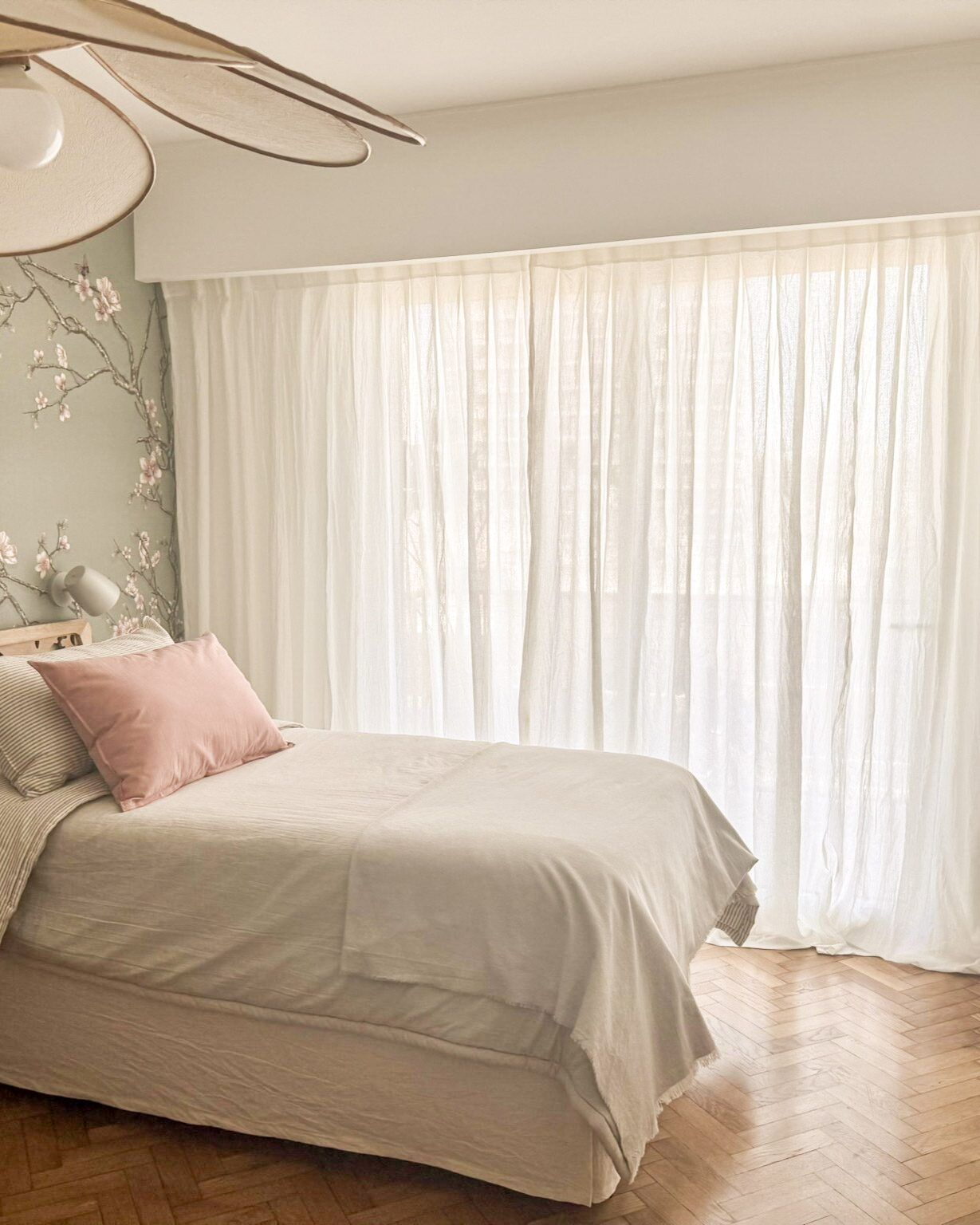 Dormitorio con cama y cortinas blancas traslúcidas.